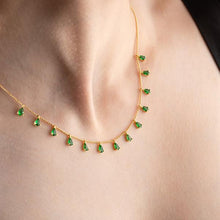 Gold necklace with green gemstones worn by a person