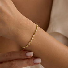 Gold bracelet on a wrist with a neutral background