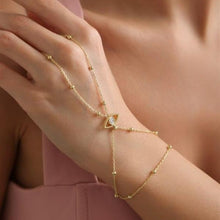 Gold bracelet with a small gemstone on a wrist against a blurred background