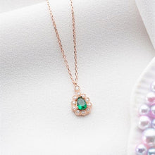 Rose gold necklace with a green gemstone pendant on a white background