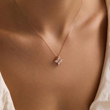 Rose gold necklace with a floral pendant on a person wearing a white shirt.