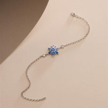 Silver bracelet with a blue flower-shaped clasp on a beige background