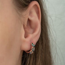 Close-up of an ear wearing a small earring with a clear gemstone.