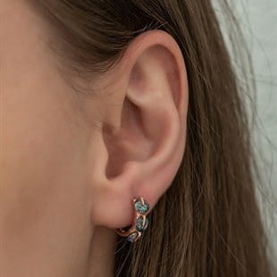 Close-up of an ear wearing a small earring with a clear gemstone.
