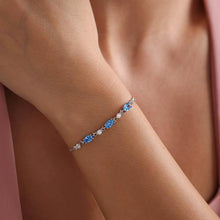 Bracelet with blue gemstones on a wrist against a pink fabric background
