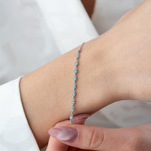 Silver bracelet with blue stones on a wrist against a neutral background