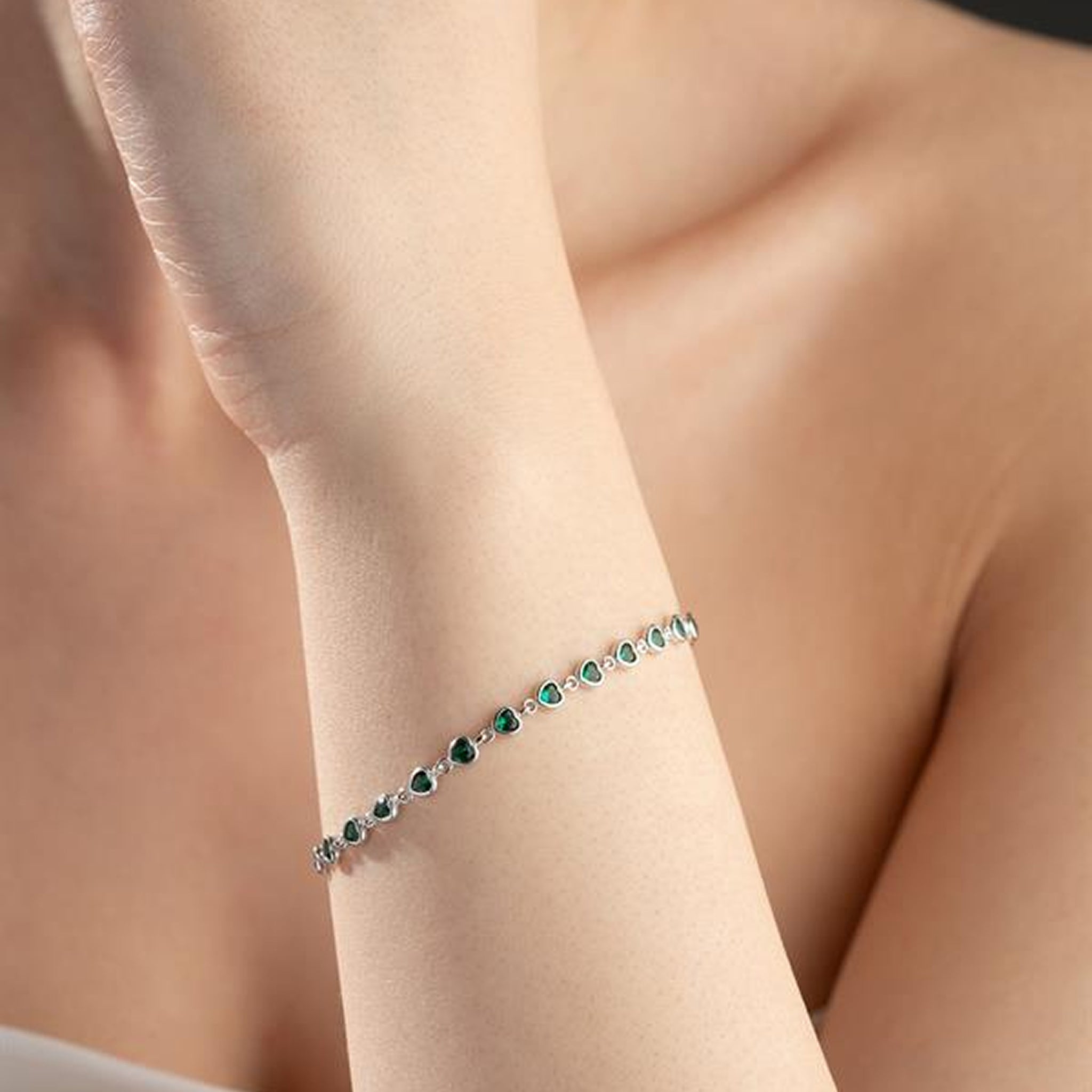Silver bracelet with green gemstones on a person's wrist