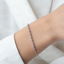 Silver bracelet with blue stones on a wrist against a white background