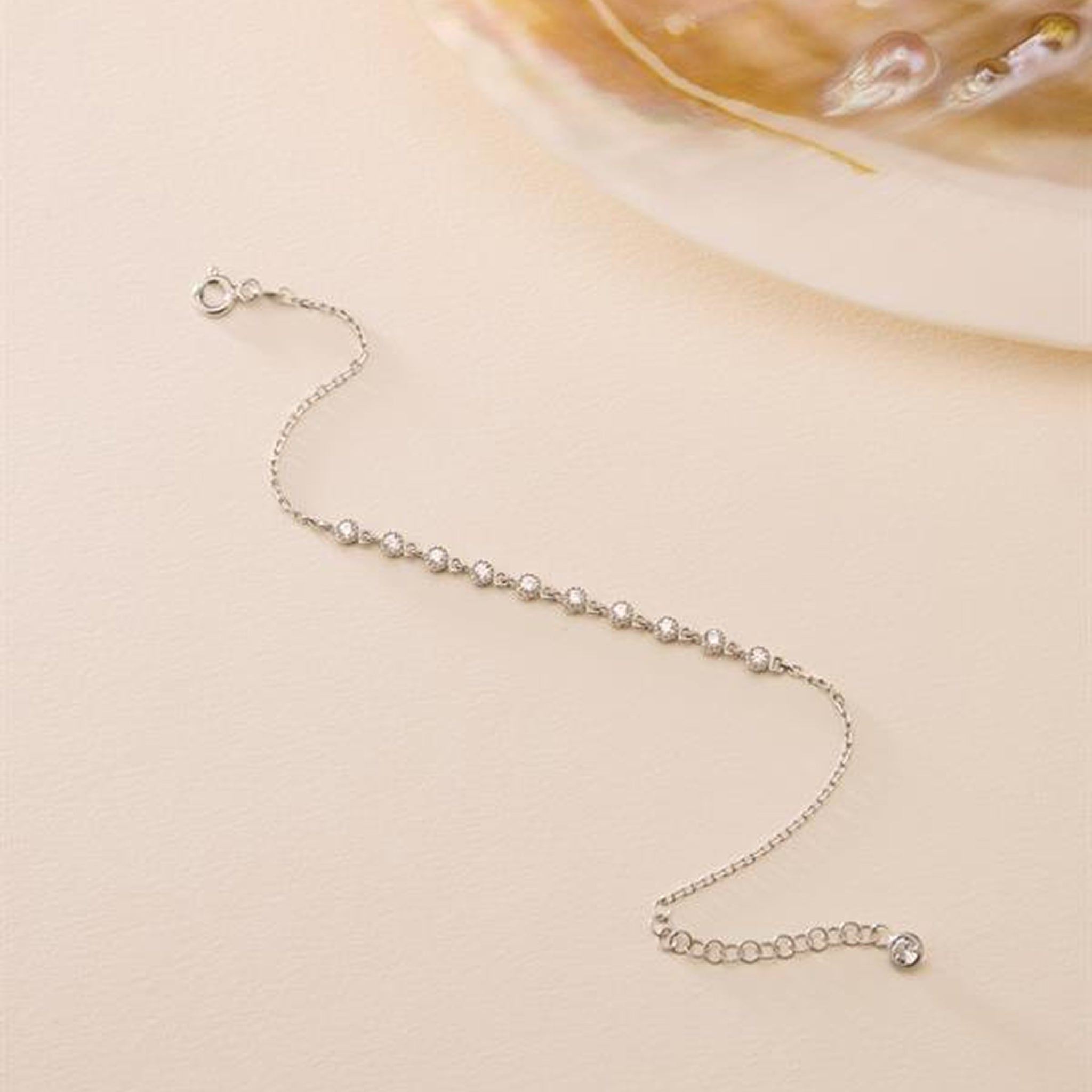 Silver bracelet with small beads on a beige background