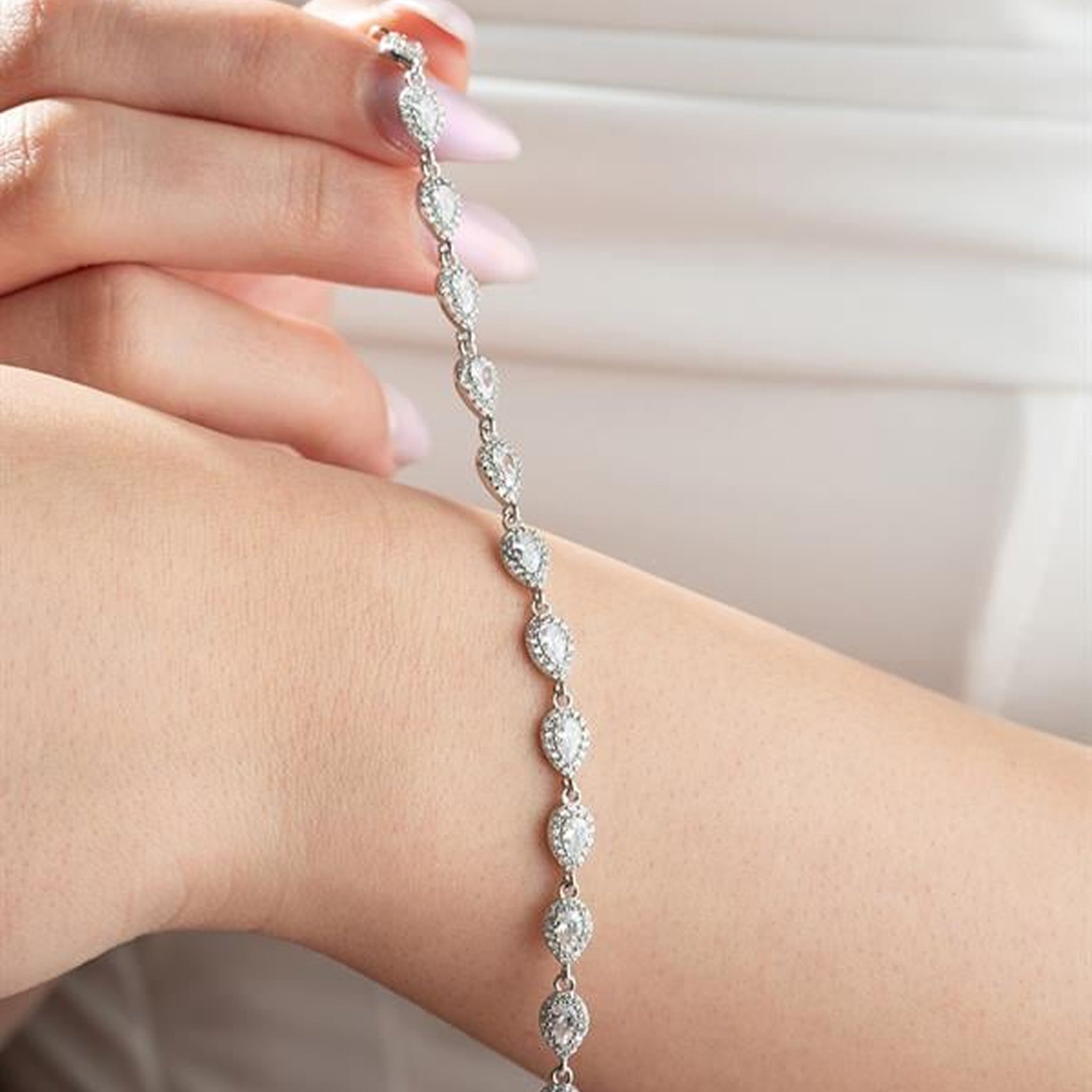 Silver bracelet with clear stones on a wrist against a neutral background
