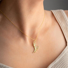 Gold necklace with a unique pendant on a person wearing a beige top.