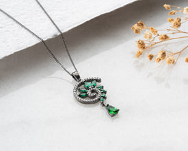 Mysterious woman wearing black rhodium emerald necklace under moonlight - perfect for dark celestial photography