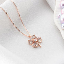 Rose gold four-leaf clover necklace on a white background